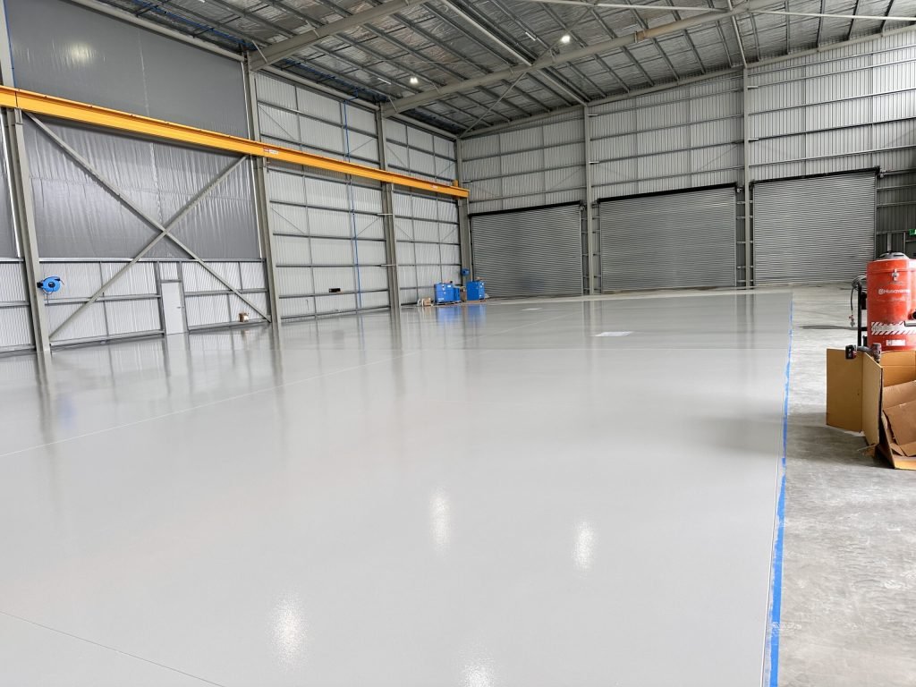 Newly installed solid epoxy flooring in a Melbourne warehouse with a seamless, high-gloss industrial floor finish.